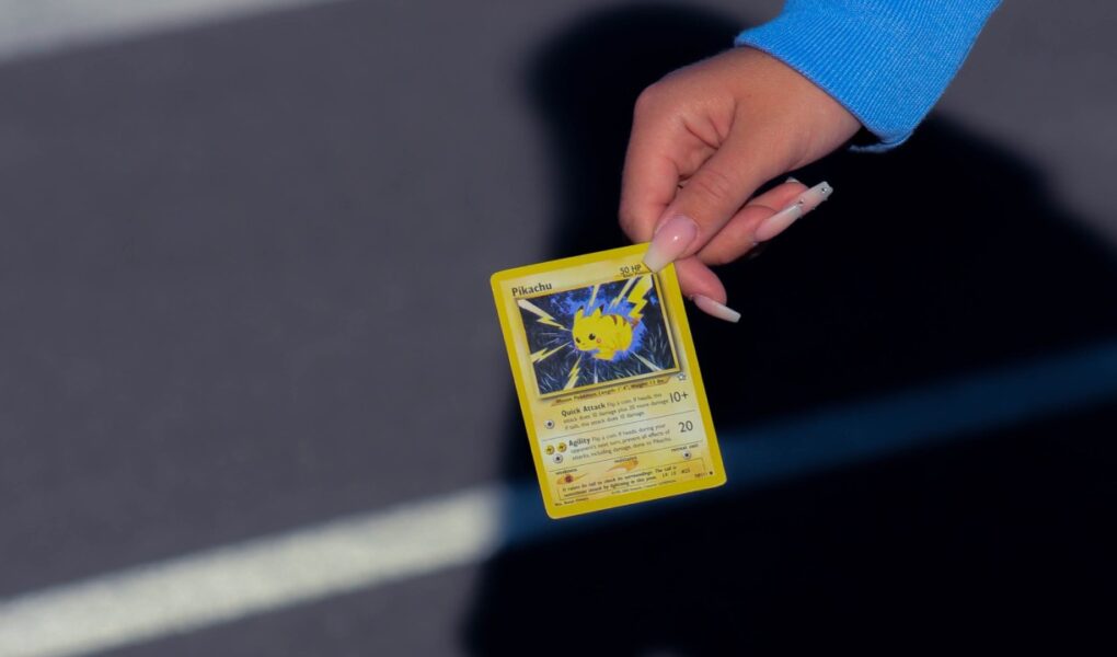 A hand holding a Pokémon card with a Pikachu on it.