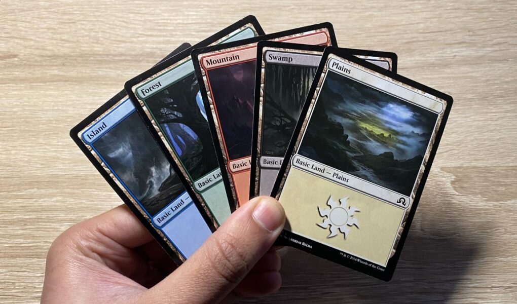 Each of the five different basic mana cards in MTG in a hand.